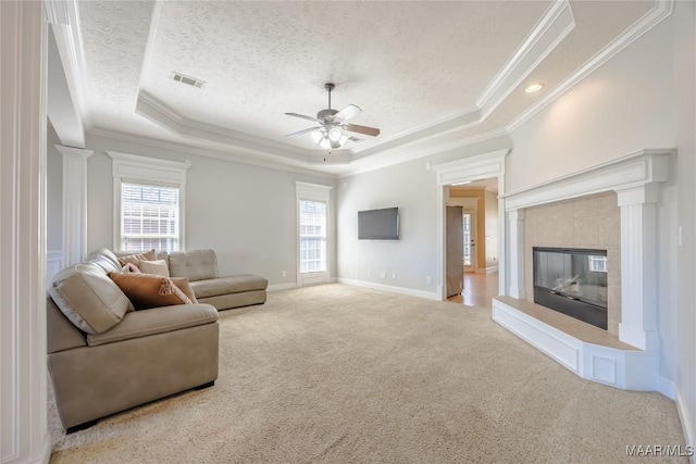 carpeted living area featuring a tray ceiling, visible vents, ornamental molding, and ceiling fan