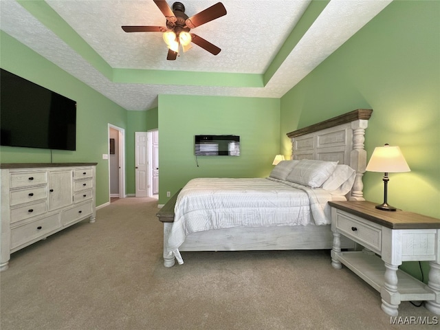 carpeted bedroom with ceiling fan, a textured ceiling, and a raised ceiling