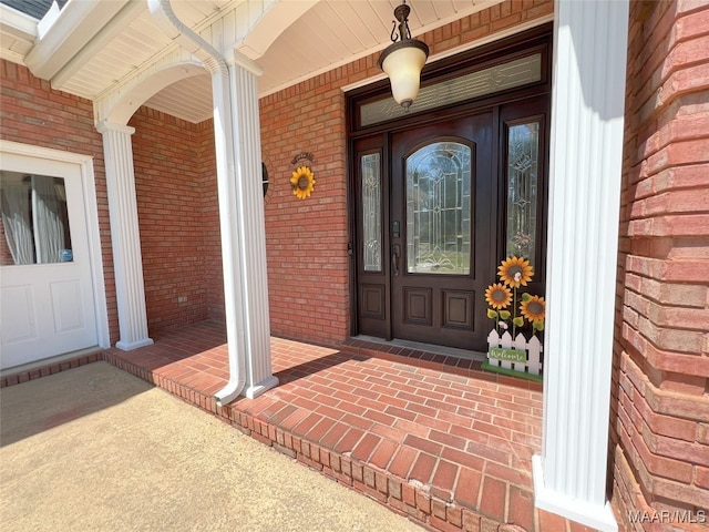 entrance to property featuring brick siding and covered porch