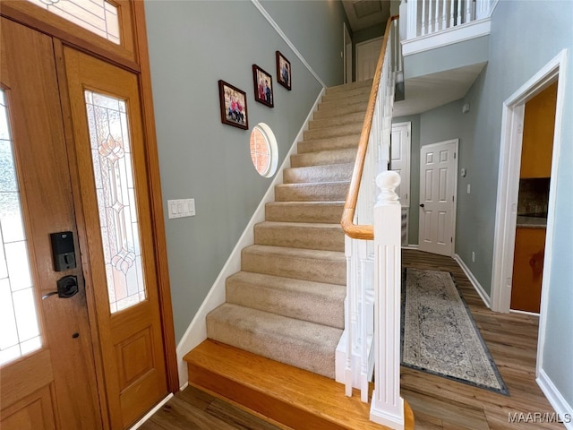 foyer featuring baseboards, wood finished floors, and stairs