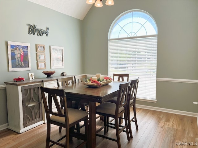 dining area featuring vaulted ceiling, baseboards, and light wood-type flooring