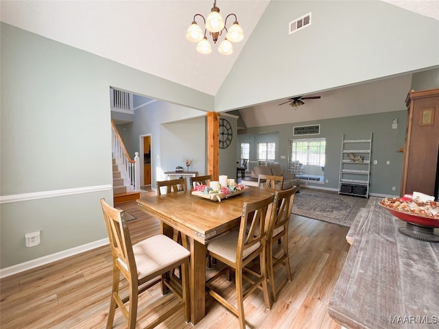 dining space featuring high vaulted ceiling, stairway, ceiling fan with notable chandelier, light wood-style flooring, and visible vents