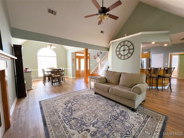 living area featuring stairway, a ceiling fan, light wood-style floors, and visible vents