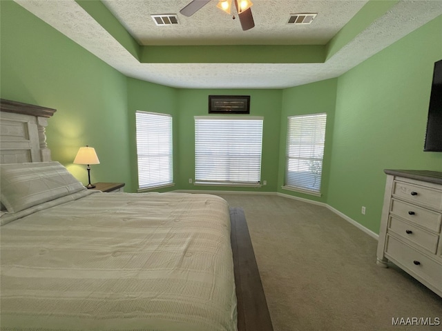 carpeted bedroom featuring a textured ceiling, visible vents, baseboards, and multiple windows