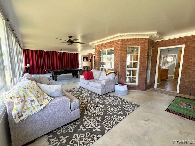 interior space featuring ceiling fan, billiards, brick wall, and finished concrete floors