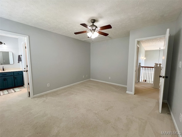 unfurnished bedroom featuring light carpet, connected bathroom, baseboards, a textured ceiling, and ceiling fan