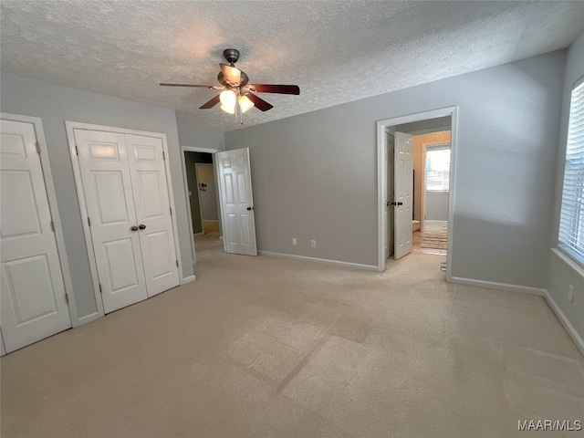 unfurnished bedroom with baseboards, a textured ceiling, and light carpet