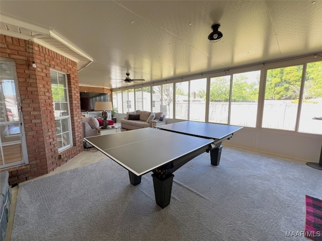 playroom with carpet, a healthy amount of sunlight, a ceiling fan, and brick wall