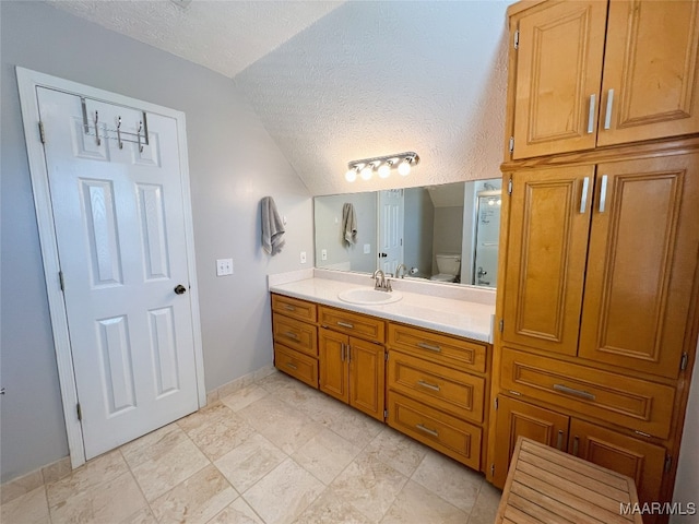 bathroom featuring vaulted ceiling, toilet, vanity, and a textured ceiling