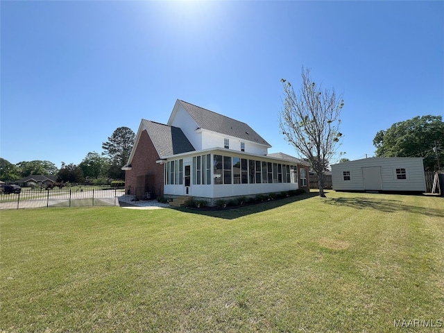 rear view of property with an outdoor structure, fence, a yard, a sunroom, and roof with shingles