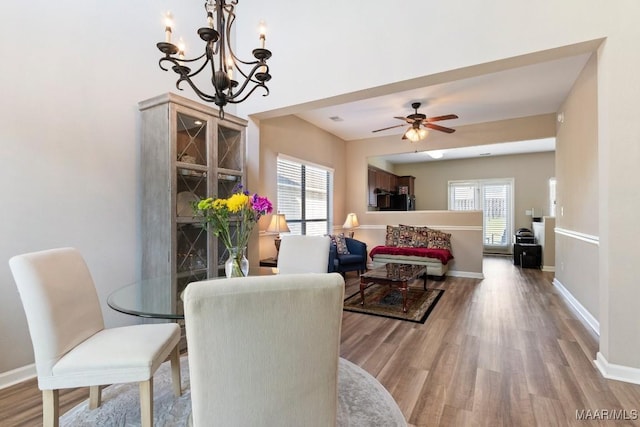 dining room with ceiling fan with notable chandelier, baseboards, and wood finished floors
