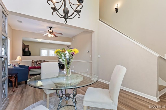 dining area featuring wood finished floors, visible vents, baseboards, and ceiling fan with notable chandelier