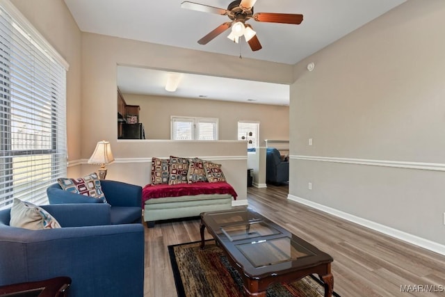 living area with baseboards, a ceiling fan, and wood finished floors