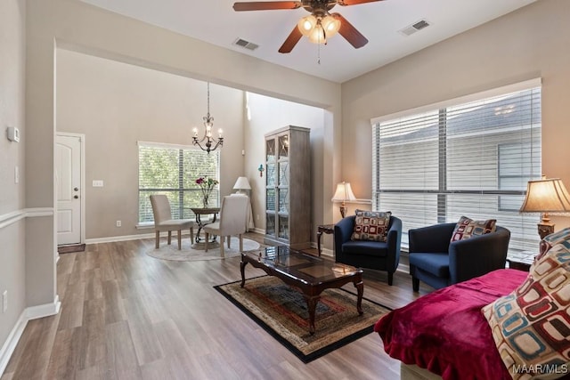 living room featuring wood finished floors, visible vents, and ceiling fan with notable chandelier