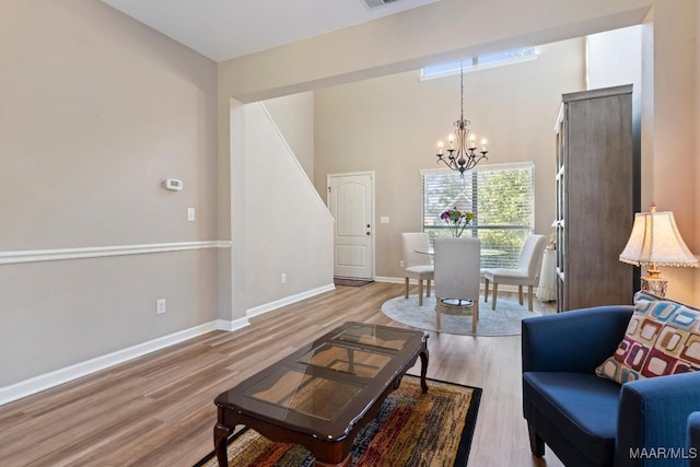 living area featuring wood finished floors, visible vents, baseboards, and a notable chandelier