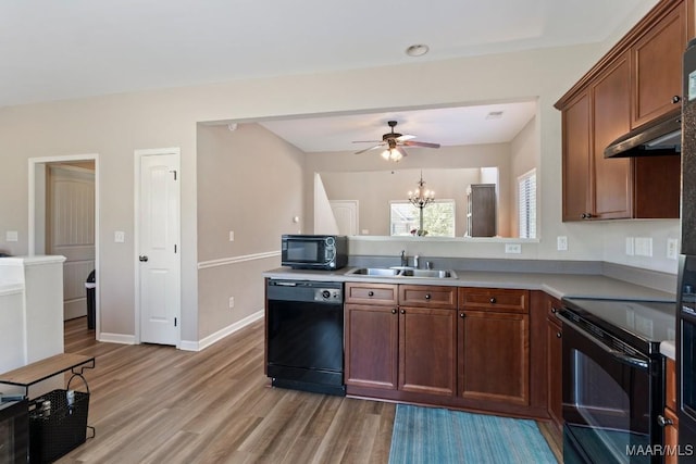 kitchen featuring a sink, ceiling fan with notable chandelier, black appliances, light wood-type flooring, and light countertops