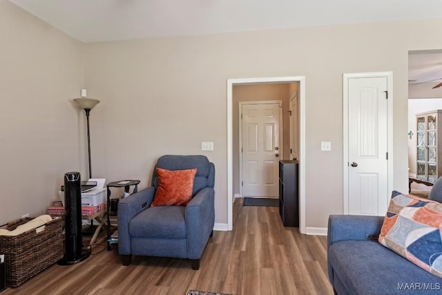 living area with ceiling fan, baseboards, and wood finished floors