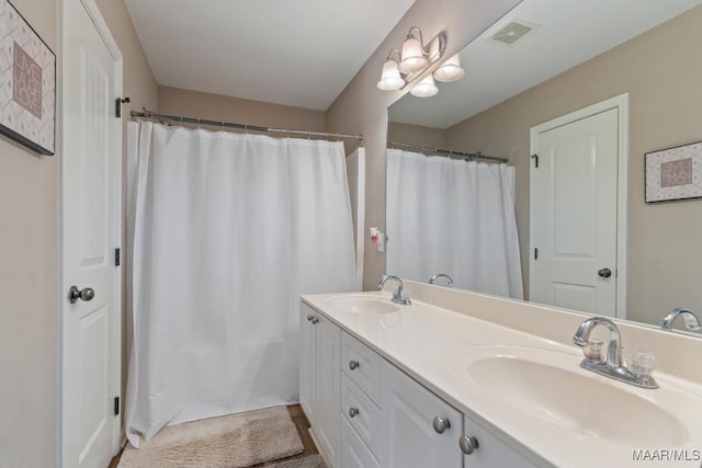 bathroom with curtained shower, double vanity, visible vents, and a sink