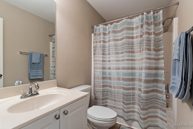 bathroom featuring a textured wall, shower / tub combo with curtain, vanity, and toilet