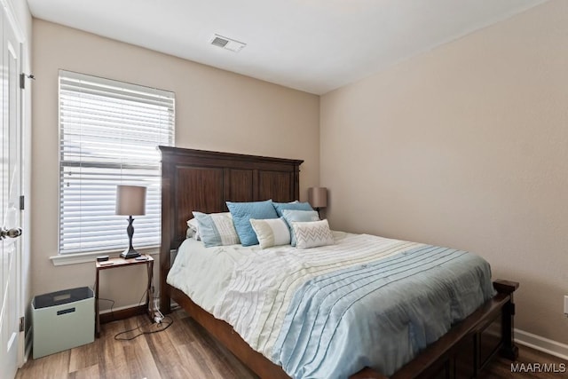 bedroom with wood finished floors, visible vents, and multiple windows