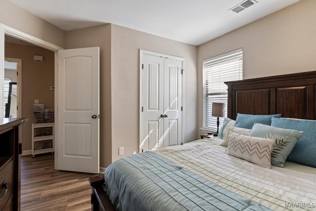 bedroom featuring visible vents, dark wood-type flooring, a closet, and multiple windows