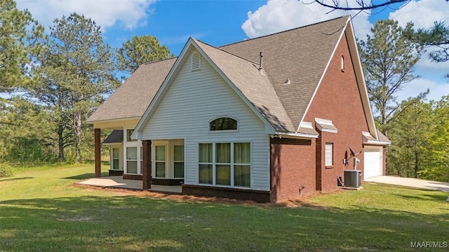 back of property with cooling unit, concrete driveway, an attached garage, a lawn, and brick siding
