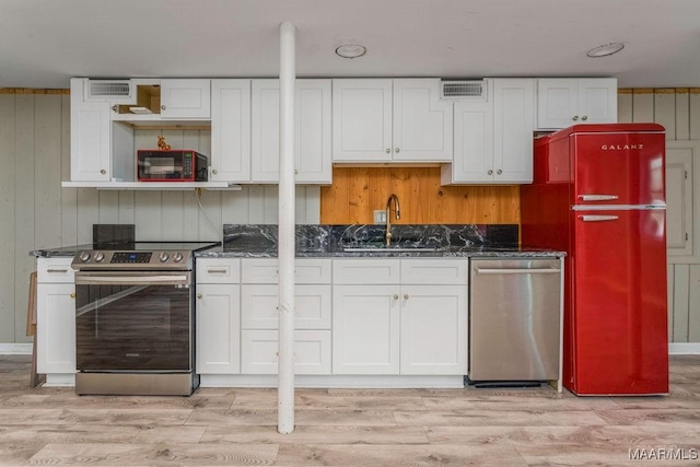 kitchen featuring stainless steel appliances, a sink, white cabinets, light wood-type flooring, and open shelves