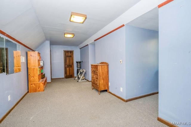 hall featuring carpet, baseboards, and lofted ceiling