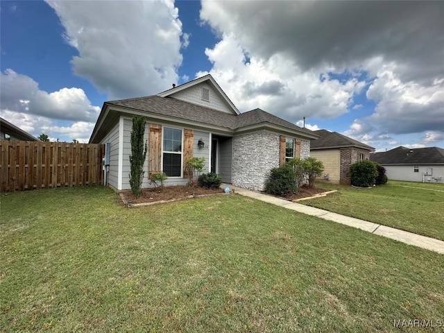 ranch-style home with a front lawn, a shingled roof, and fence