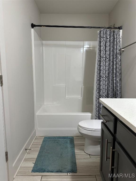 full bath featuring shower / bath combo, baseboards, toilet, wood finished floors, and vanity