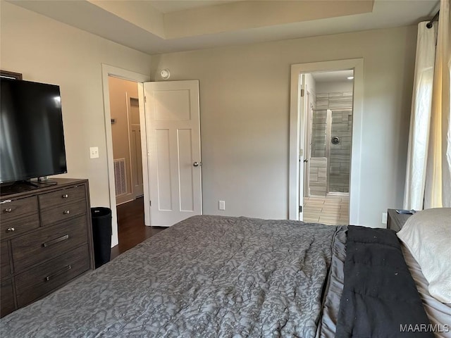 bedroom featuring ensuite bath, wood finished floors, and visible vents