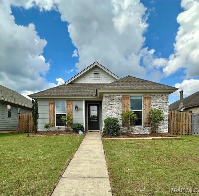bungalow-style home with a front yard, stone siding, and fence