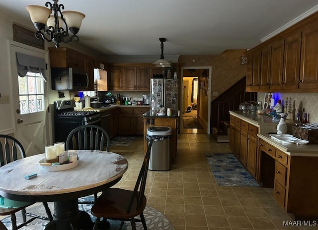 kitchen with a center island, an inviting chandelier, stainless steel appliances, pendant lighting, and backsplash