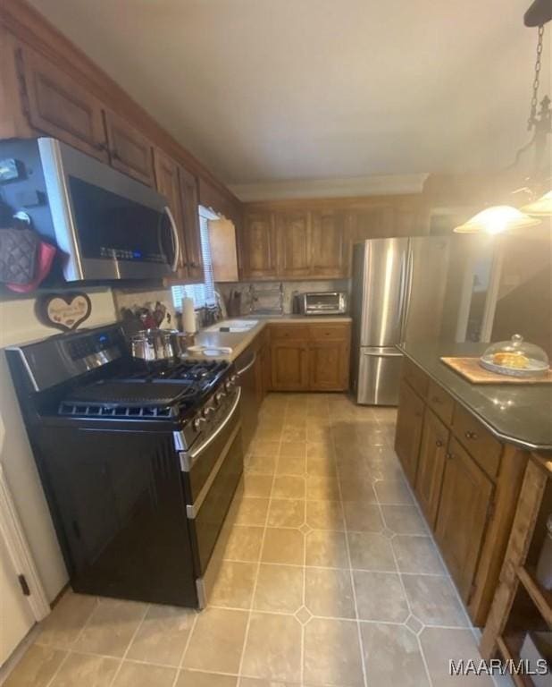 kitchen featuring a sink, brown cabinetry, light tile patterned floors, stainless steel microwave, and gas stove