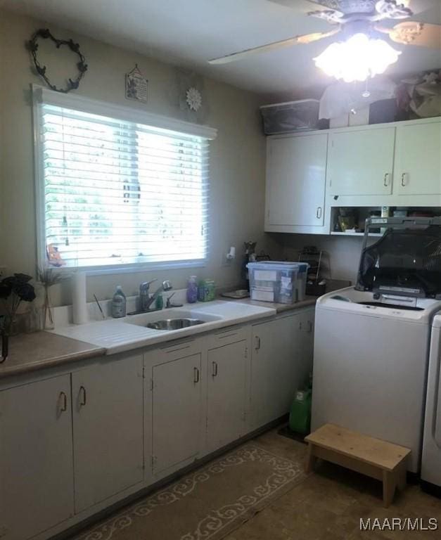 kitchen with washer / clothes dryer, a sink, white cabinetry, and light countertops