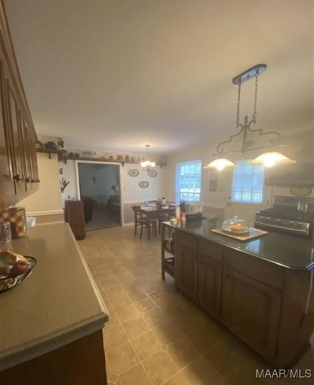 kitchen featuring dark countertops, light floors, a notable chandelier, gas stove, and a kitchen island