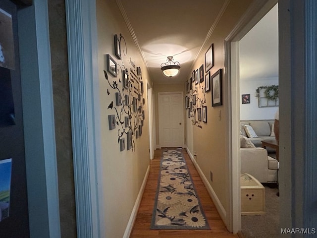 corridor featuring light wood-style flooring, baseboards, and ornamental molding