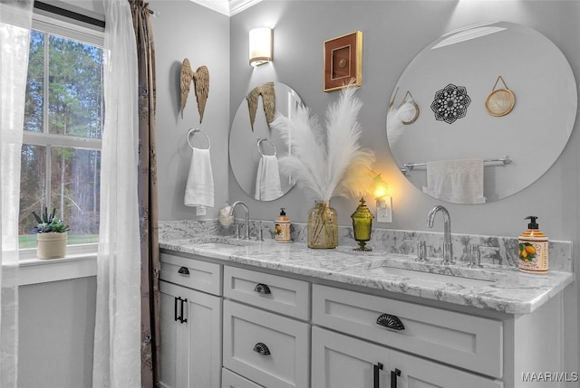 full bath featuring double vanity, crown molding, and a sink