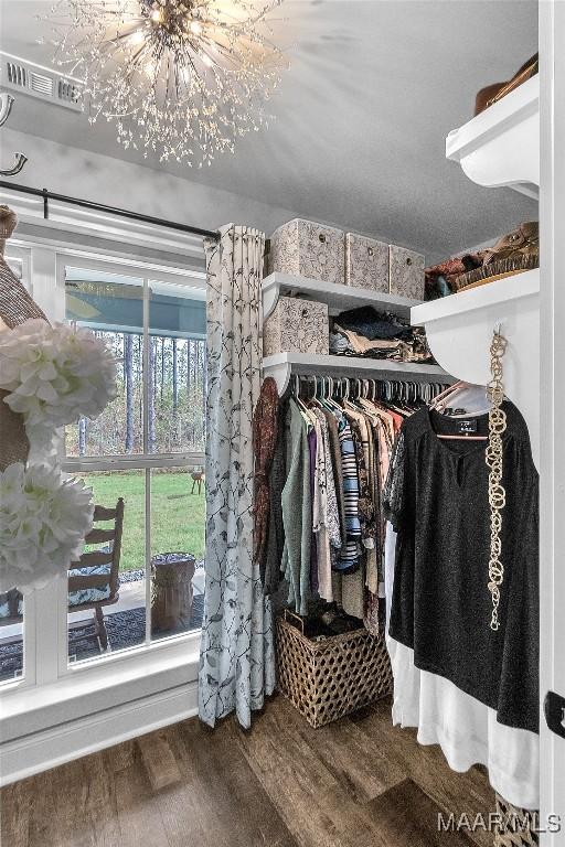 spacious closet with wood finished floors and an inviting chandelier