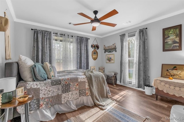 bedroom featuring ornamental molding, wood finished floors, and visible vents