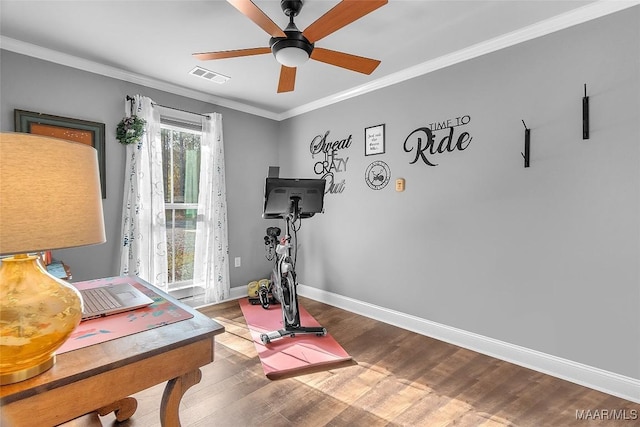 workout area featuring baseboards, visible vents, a ceiling fan, wood finished floors, and crown molding
