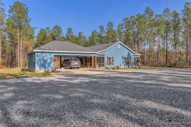 view of front of house with driveway, a carport, and a shingled roof