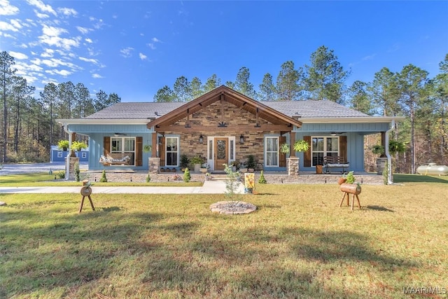 view of front of home featuring stone siding, a front yard, and covered porch