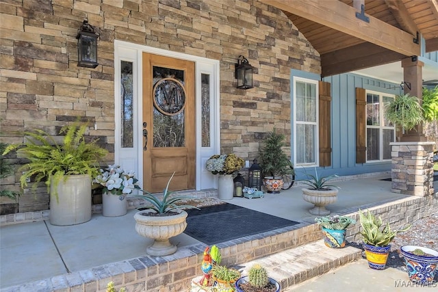 doorway to property with stone siding and covered porch