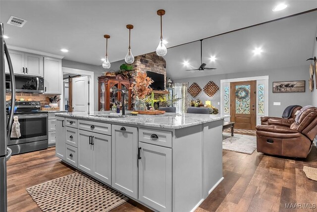 kitchen featuring a sink, open floor plan, dark wood finished floors, appliances with stainless steel finishes, and recessed lighting