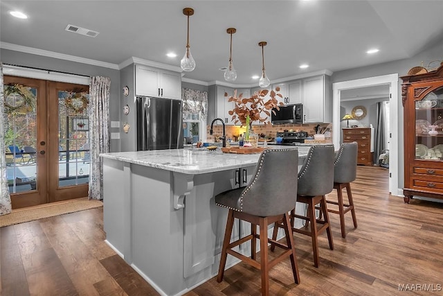 kitchen with recessed lighting, backsplash, wood finished floors, ornamental molding, and appliances with stainless steel finishes