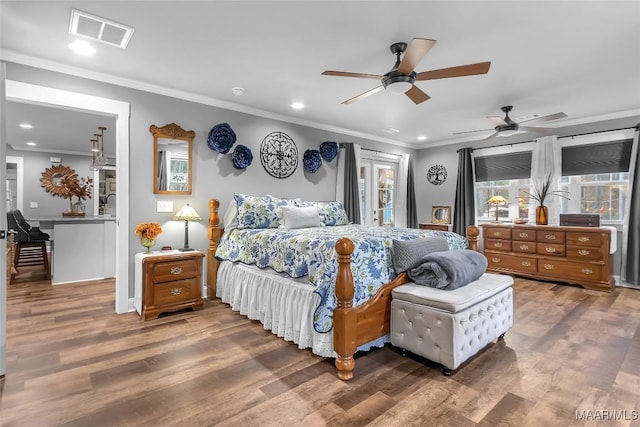 bedroom with recessed lighting, wood finished floors, visible vents, and ornamental molding