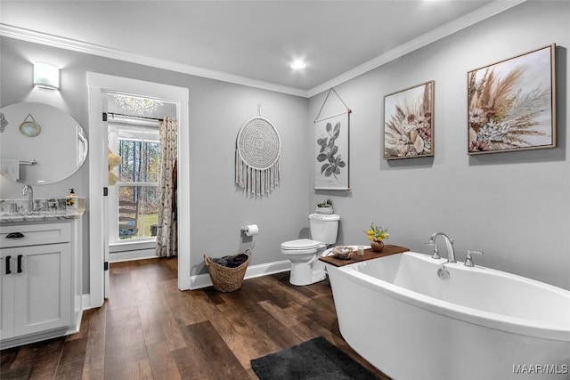 full bathroom featuring wood finished floors, toilet, vanity, ornamental molding, and a freestanding tub