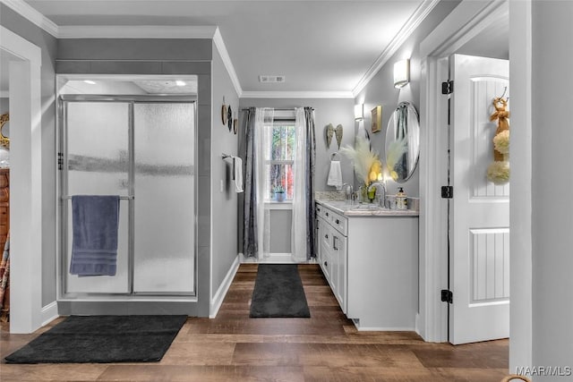 bathroom featuring vanity, wood finished floors, a shower stall, and crown molding