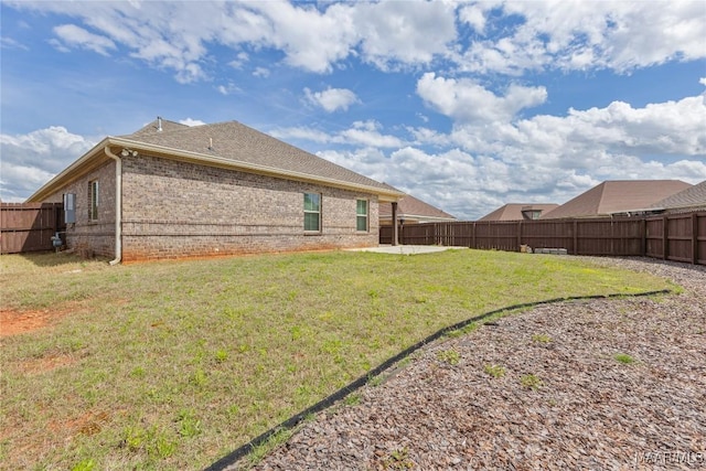 exterior space featuring a lawn, a fenced backyard, brick siding, and a patio